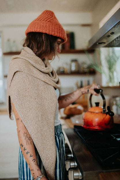 Woman in a kitchen wearing a beige shawl.