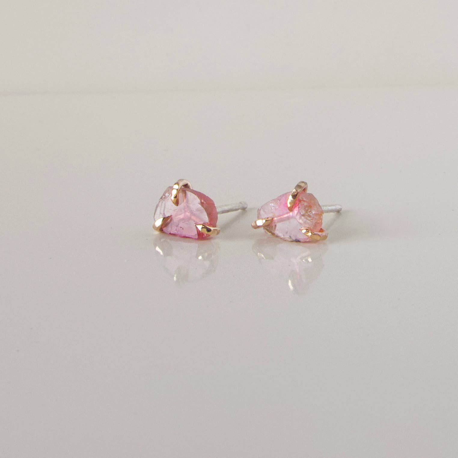 Pair of pink heart-shaped tourmaline stud earrings with gold accents.
