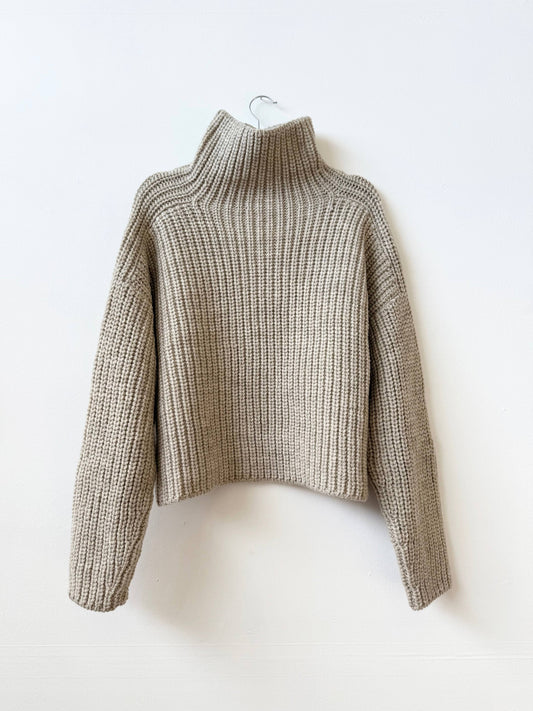 Knitted sweater on a hanger against a white background