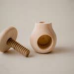 A wooden mushroom screw top toy for babies.
